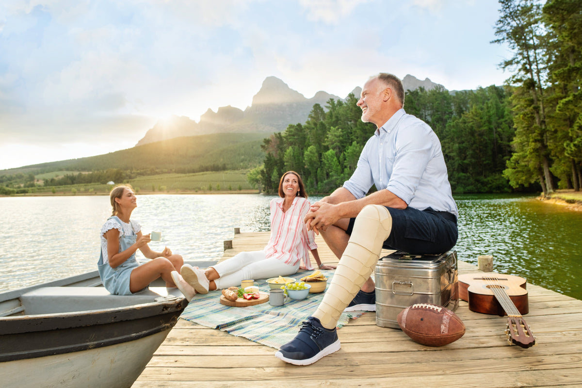 Family sitting on a dock by a lake with mountains in the background