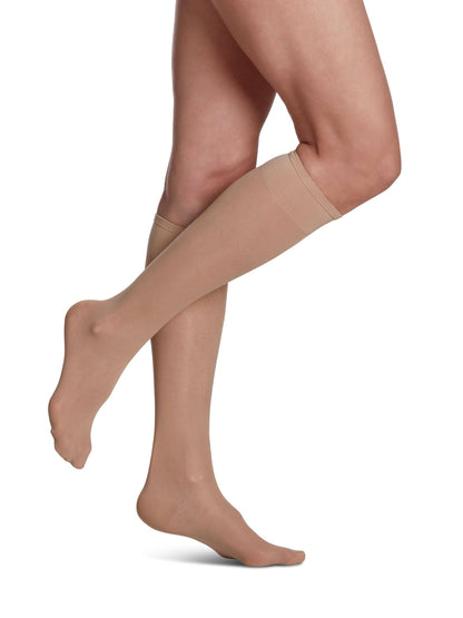 Beige compression stockings worn by a person on a white background