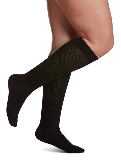 Black knee-high socks worn by a person on a white background