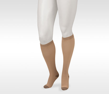Beige knee-high socks worn with white pants on a light gray background. Discover the Juzo Compressionsale collection of compression hosiery designed for comfort, support, and everyday wear.