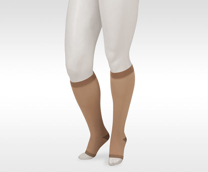 Beige knee-high socks worn with white leggings on a light gray background. Shop the Juzo Compressionsale collection of compression hosiery for comfort, support, and everyday wear.”