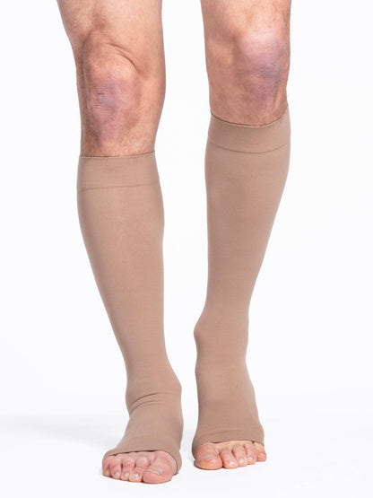 Beige compression stockings worn by a person on a white background