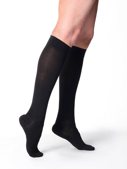 Black knee-high socks worn by a person on a white background