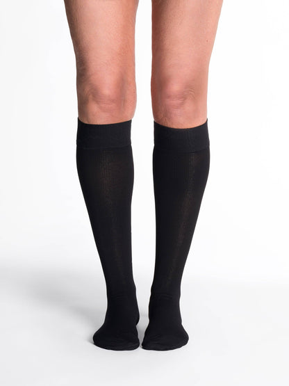 Black compression stockings being worn on a white background