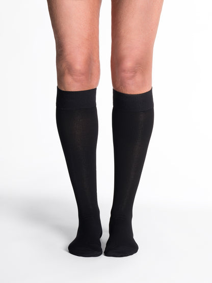 Black knee-high socks worn by a person on a white background