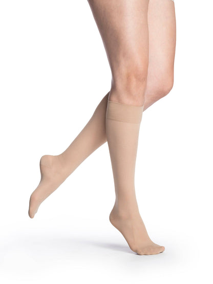 Beige sheer stockings worn by a person on a white background