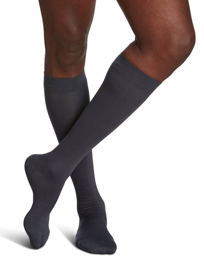 Dark gray knee-high socks worn by a person on a white background