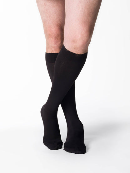 Black knee-high socks worn by a person on a white background