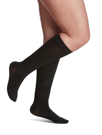 Black knee-high socks worn by a person on a white background