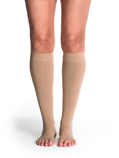 Beige compression stockings worn by a person on a white background
