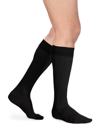 Black knee-high socks worn by a person on a white background