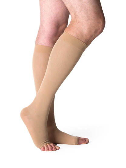 Beige compression stockings being worn on a white background