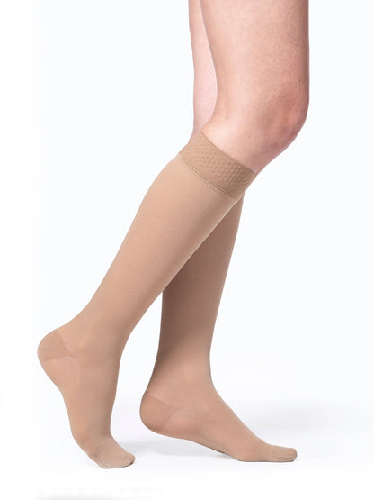 Beige compression stockings worn by a person on a white background