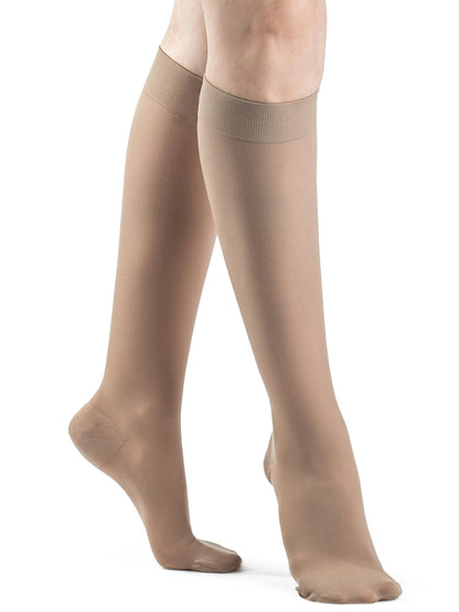 Beige compression stockings worn by a person on a white background