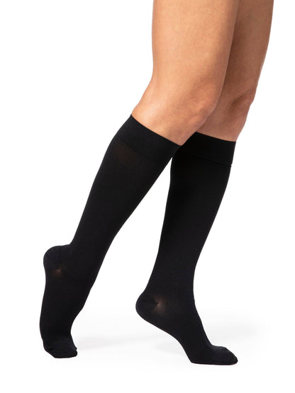 Black knee-high socks worn by a person on a white background