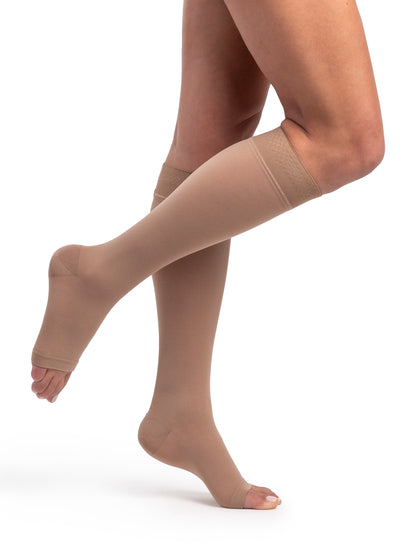 Beige compression stockings being worn on a white background