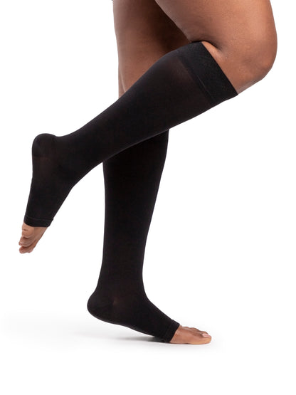 Black compression stockings being worn on a white background