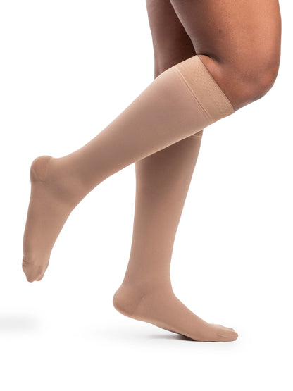 Beige compression stockings worn by a person on a white background