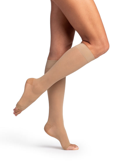 Beige compression stockings being worn on a white background