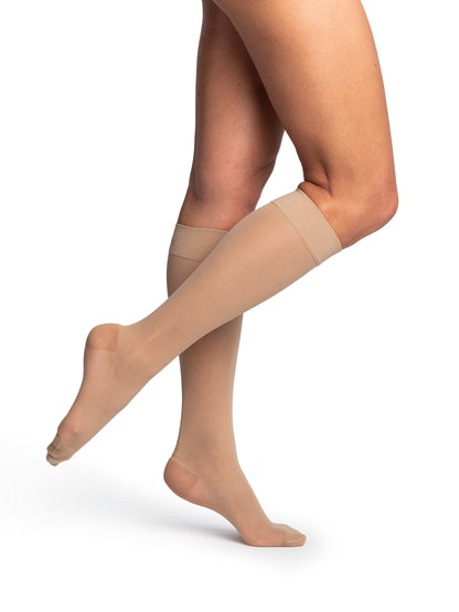 Beige compression stocking worn by a person on a white background