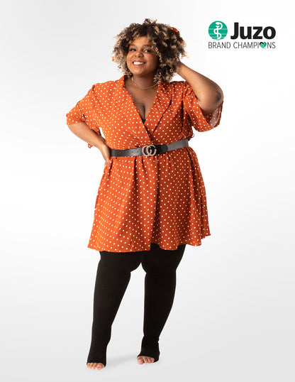Woman wearing an orange polka dot dress with a belt on a white background, with the Juzo logo visible. Explore the Juzo Compressionsale collection of compression hosiery and accessories designed for comfort, support, and everyday wear