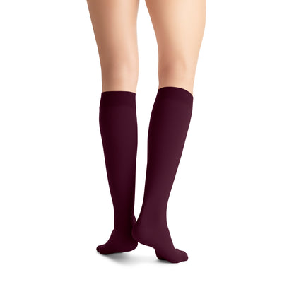 Dark purple knee-high socks worn by a person on a white background