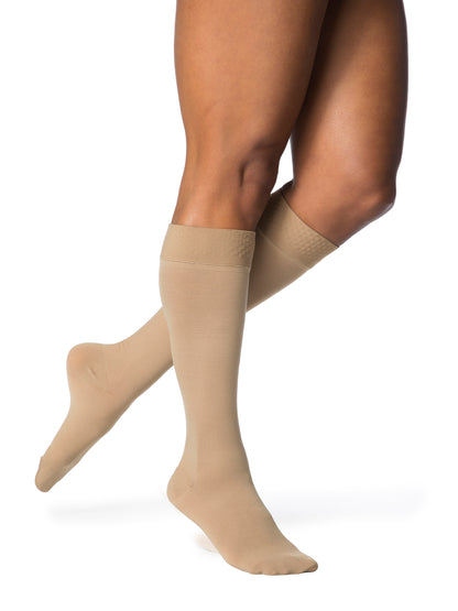 Beige compression socks worn by a person on a white background