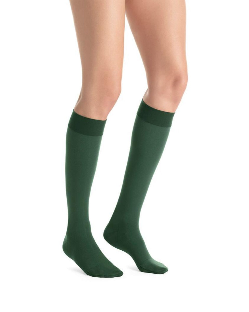Green knee-high socks worn by a person on a white background