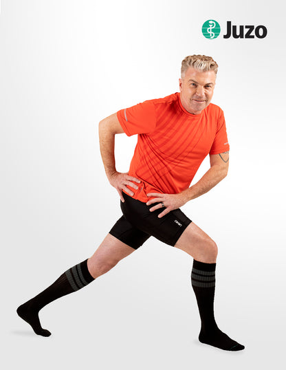 Man wearing black compression stockings with the Juzo logo on a white background. Discover the Juzo Compressionsale collection of compression hosiery designed for comfort, support, and everyday wear.