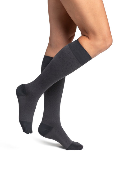 Dark gray knee-high socks worn by a person on a white background