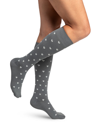 Gray knee-high socks with heart pattern worn by a person on a white background