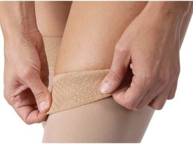 Person applying a beige bandage to their knee