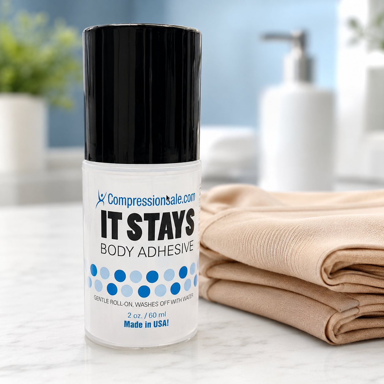 It Stays Body Adhesive roll-on next to folded beige compression stockings on a bathroom counter
