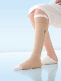 Person wearing a white knee-high sock from Compressionsale on a light blue background.