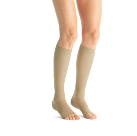 Beige compression socks worn by a person from Compressionsale on a white background.