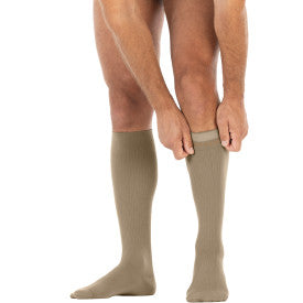 Person wearing beige compression socks on a white background