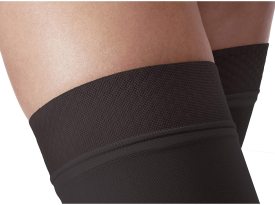 Black compression bandage on a person's leg against a neutral background