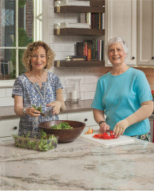 Two women preparing food in a kitchen.