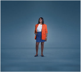 Woman wearing an orange blazer and blue skirt against a blue background