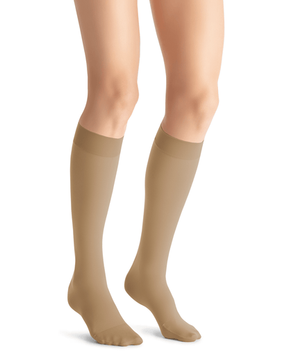 A pair of knee-high compression stockings in a natural color, featuring a closed toe design.